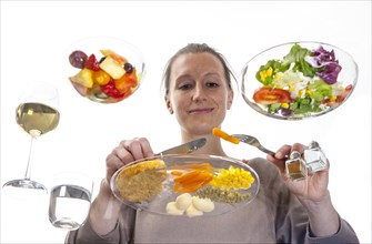 Young woman sitting at a glass table eating steak with vegetables and potatoes