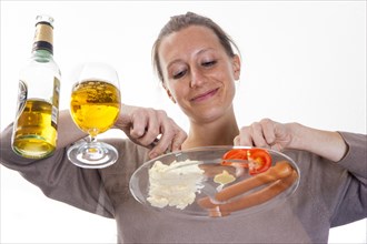 Young woman sitting at a glass table eating Frankfurter sausages with potato salad