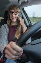 Young woman driving a car while talking on her cell phone