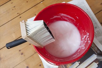 Bucket of wallpaper paste and a brush