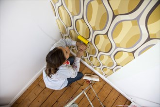 Young woman wallpapering a wall