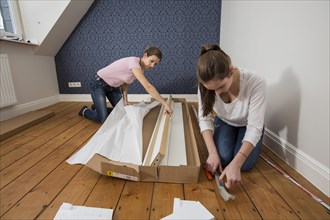 Mother and daughter working together to assemble a bed in the daughter's room