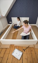 Mother and daughter working together to assemble a bed in the daughter's room