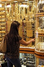 Woman looking at gold jewellery in a shop window