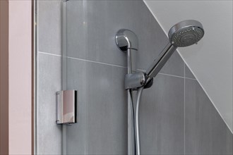 Shower head in the shower on tiled wall