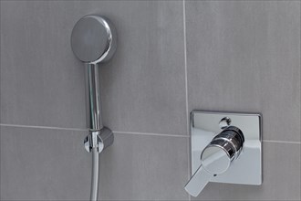 Modern shower head and bathroom fitting on tiled wall