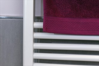 Berry-colored towel hanging on a radiator to dry