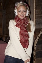 Young woman wearing ear warmers and a scarf standing in a hiking hut