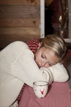 Young woman wearing a scarf sitting and sleeping at the table of a hiking hut