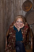 Smiling young woman wrapped in a blanket in a hiking hut
