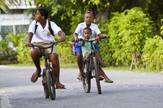 Children wearing school uniforms while cycling