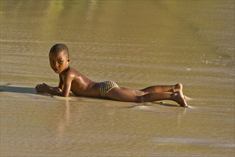 Creole boy lying on a beach
