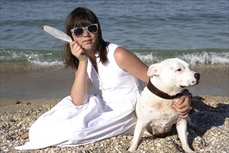 Girl sitting on the beach with a Staffordshire Bull Terrier