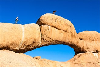 Young men climbing a rock arch