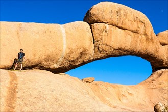 Young man climbing a rock arch