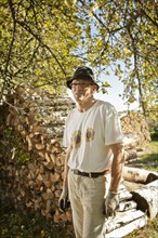 Man in the orchard in front of a wood pile