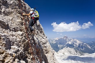 Mountaineer climbing the Via Ferrata Ivano Dibona climbing route to the summit of Monte Cristallo to the summit of Cristallino above Cortina