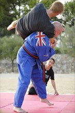 A martial arts instructor is demonstrating a shoulder throw with a student