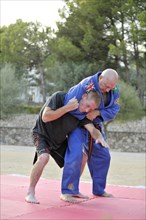 Martial arts instructor holding his student in a headlock during a training session in a park