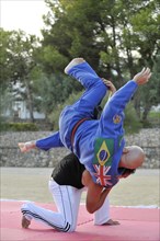 A martial arts instructor is demonstrating a shoulder throw with a student