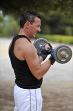 Man lifting weights while exercising in a park