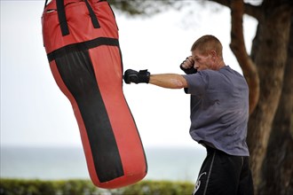 Man practicing punches on a punching bag in a park