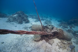 An anchor made of concrete blocks and old barrels in the coral reef