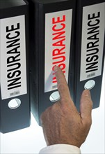 Hand pointing to a ring binder labelled 'INSURANCE'