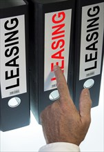 Hand pointing to a ring binder labelled "LEASING"
