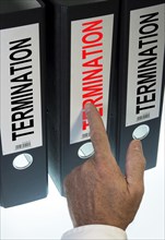 Hand pointing to a file folder labeled 'Termination'