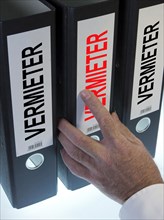 Hand reaching for a file folder labeled "Vermieter"