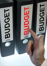 Hand pointing to a ring binder labelled 'BUDGET'