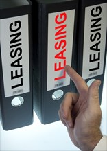 Hand pointing to a ring binder labelled 'LEASING'