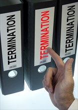 Hand pointing to a ring binder labelled 'TERMINATION'