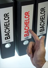 Hand pointing to a file folder labeled 'Bachelor'