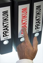 Hand pointing to a file folder labeled "Praktikum"