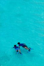 Two people snorkelling in a blue lagoon