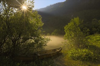 Rowing boat in the morning mist with sunrays