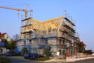 Shell of a multistory apartment building with finished roof and construction crane