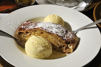 Apple strudel served with vanilla ice cream on a white plate