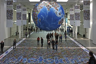 Installation depicting the global flood of images on a globe and on the floor in an exhibition hall