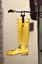 Gold-coloured boot as a hanging sign on a former shoemaker shop