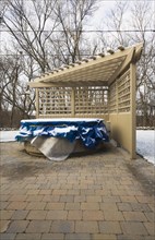 Wooden pergola and a spa in a residential backyard covered up for the winter season