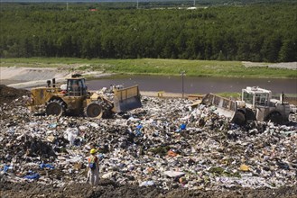 Heavy machinery spreading out and compacting discarded debris and trash at a waste management site