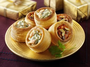 Vol-au-vents filled with salmon and dill cream and olive tapenade on a gold plate with gold presents
