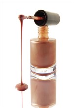 Nail varnish dripping from a nail varnish brush balanced on a nail varnish bottle