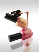 Pink nail varnish dripping from a nail varnish brush balanced on a nail varnish bottle