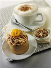 A modern Japanese cake with a pattered chocolate case and piped chestnut puree with cumquat sauce