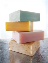 Four bars of scented hand-made soaps piled on aluminium with water droplets