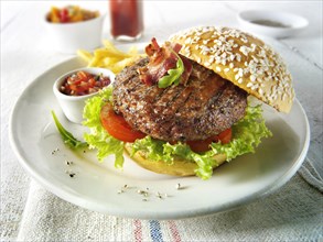 Char-grilled beef burger and bacon with chips and salad and a sesame bun